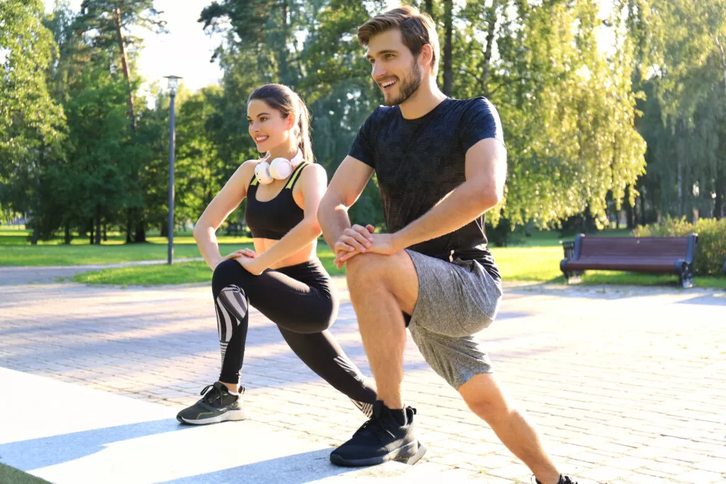 Happy young couple exercising together in a park.